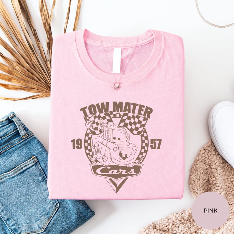 a pink t-shirt with a graphic design of a cartoon car, along with a pair of jeans and a beige sweater.