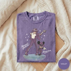 A purple t-shirt with a graphic design featuring a man and a character, likely from a Disney movie, along with the text "Michael Jackson" and "Mickey Mouse".