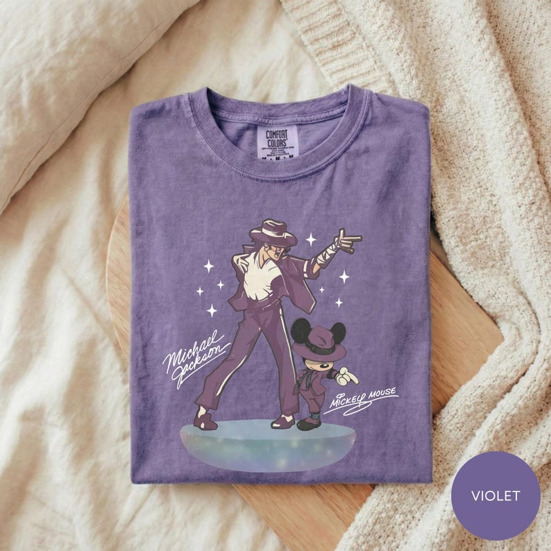 A purple t-shirt with a graphic design featuring a man and a character, likely from a Disney movie, along with the text "Michael Jackson" and "Mickey Mouse".