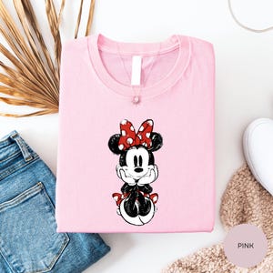 a pink t-shirt with a Minnie Mouse design, a pair of blue jeans, and some other clothing items.