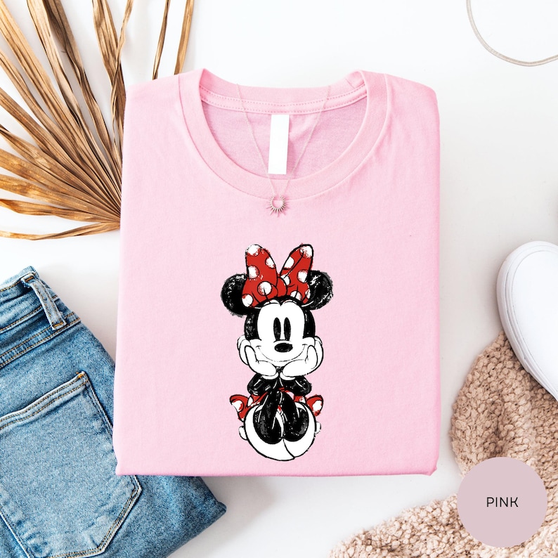 a pink t-shirt with a Minnie Mouse design, a pair of blue jeans, and some other clothing items.