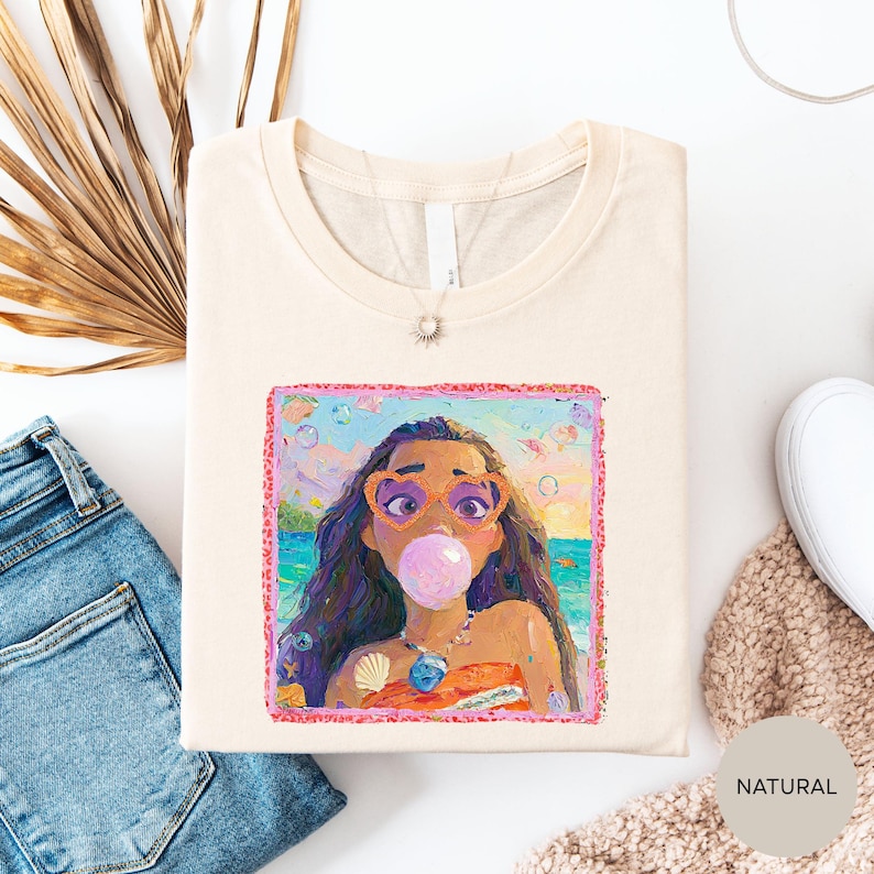 a white t-shirt with a colorful illustration of a woman blowing a bubble gum bubble, surrounded by various casual clothing items such as jeans and a sweater.