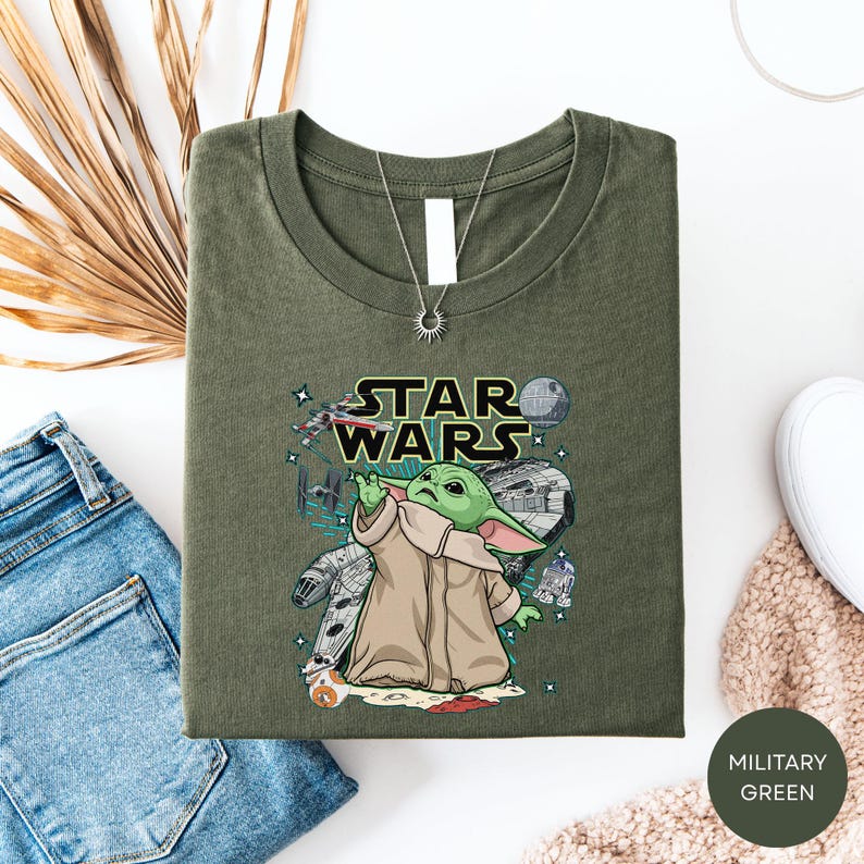 a green t-shirt with a Star Wars graphic and a small illustration of a character, along with a pair of jeans and some other clothing items.