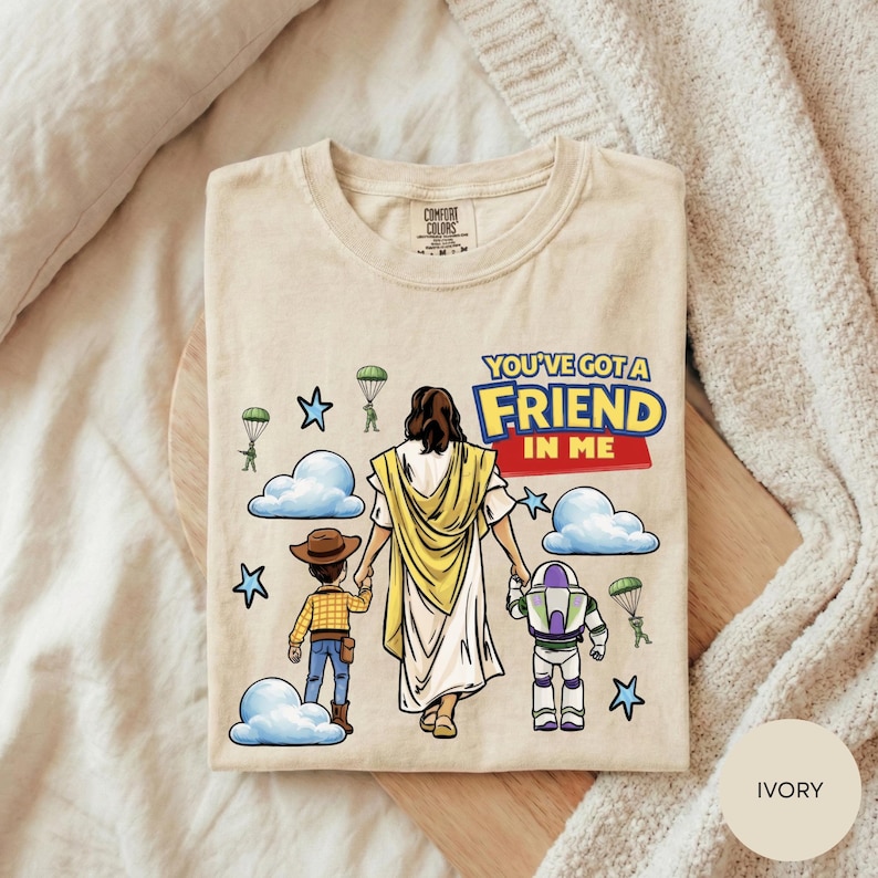 A t-shirt with a cartoon illustration of a person holding hands with a child and a robot, along with the text "You've got a friend in me" and various other cartoon characters.