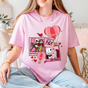 A woman wearing a pink t-shirt with a graphic design featuring characters from the movie " Nightmare Before Christmas".