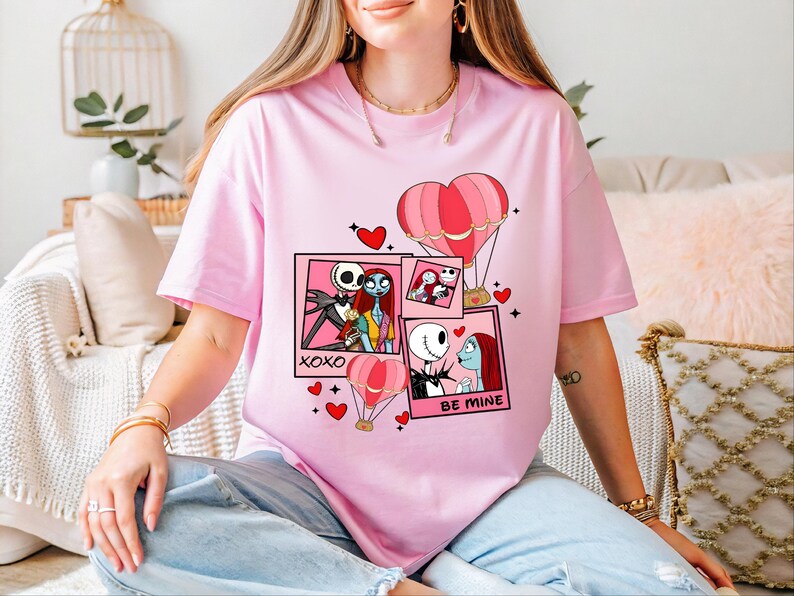 A woman wearing a pink t-shirt with a graphic design featuring characters from the movie " Nightmare Before Christmas".