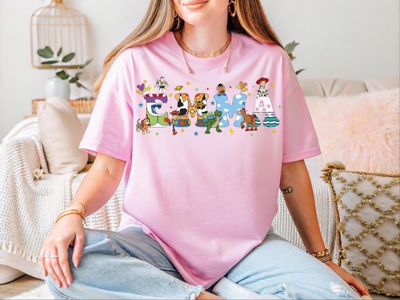A woman wearing a pink t-shirt with a colorful graphic design of characters from Toy Story.
