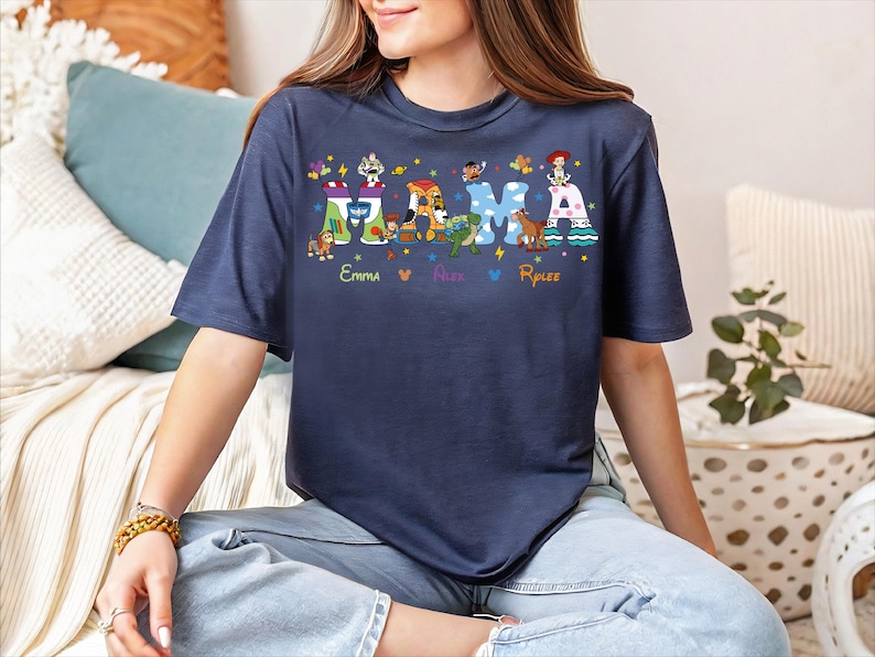 A woman wearing a blue t-shirt with a colorful graphic design of characters and text.