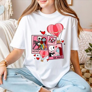 A woman wearing a white t-shirt with a graphic design featuring characters from the movie " Nightmare Before Christmas".
