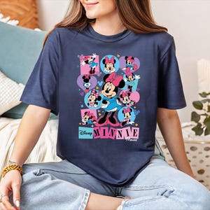A woman wearing a blue t-shirt with a graphic of Minnie Mouse and the Disney logo.