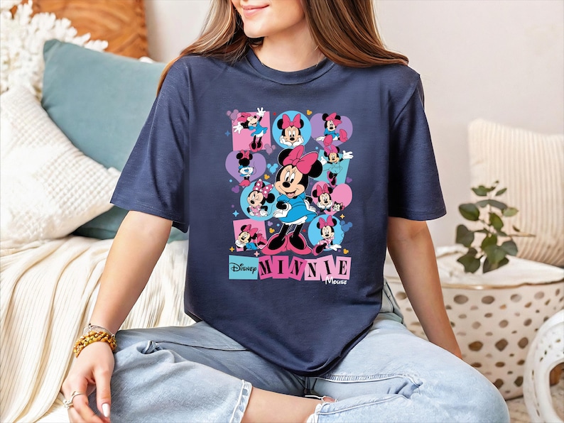 A woman wearing a blue t-shirt with a graphic of Minnie Mouse and the Disney logo.