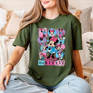 A woman wearing a green t-shirt with a collage of Minnie Mouse images is sitting on a couch.