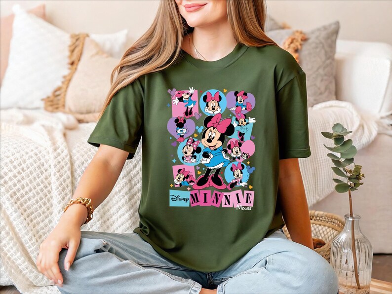 A woman wearing a green t-shirt with a collage of Minnie Mouse images is sitting on a couch.