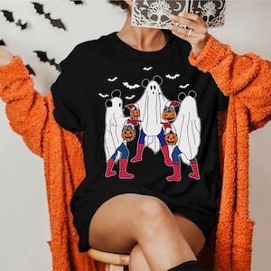 A person wearing a black t-shirt with a Halloween-themed graphic of ghostly figures and a spider-man character.