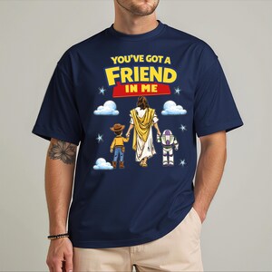 A man wearing a blue t-shirt with a graphic design featuring a cartoon character holding hands with two other characters, along with the text "You've got a FRIEND in ME".