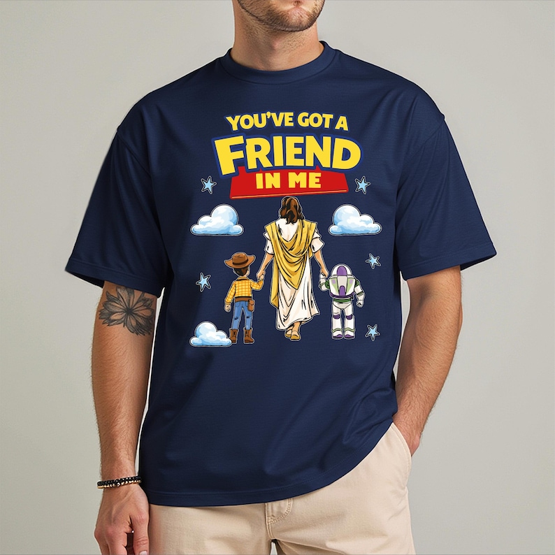 A man wearing a blue t-shirt with a graphic design featuring a cartoon character holding hands with two other characters, along with the text "You've got a FRIEND in ME".