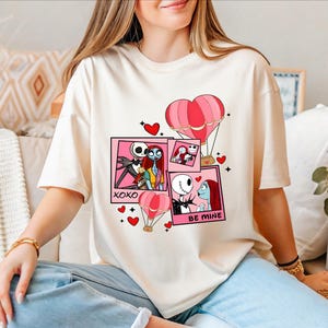A woman wearing a white t-shirt with a graphic design featuring characters from the movie " Nightmare Before Christmas".