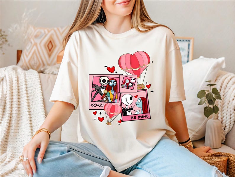 A woman wearing a white t-shirt with a graphic design featuring characters from the movie " Nightmare Before Christmas".