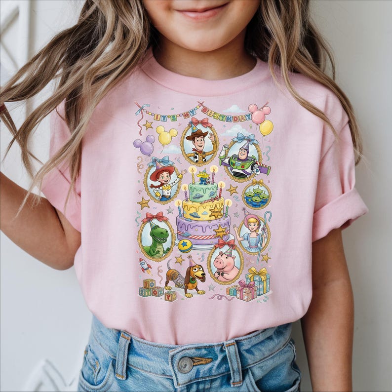 A young girl wearing a pink t-shirt with a colorful graphic of characters from the Toy Story movie, including Woody, Buzz Lightyear, and other beloved characters.