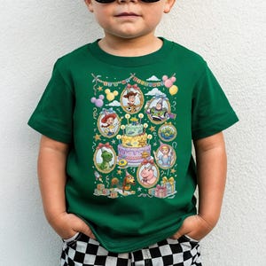 A young boy wearing a green t-shirt with a colorful graphic of characters from the Toy Story movie.