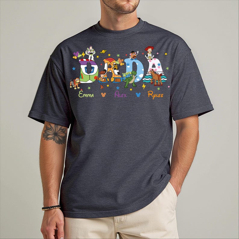 A man wearing a gray t-shirt with a colorful graphic design featuring characters from the Toy Story franchise.