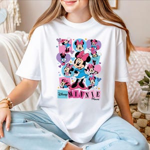 A woman wearing a white t-shirt with a Minnie Mouse graphic and text, sitting on a couch.