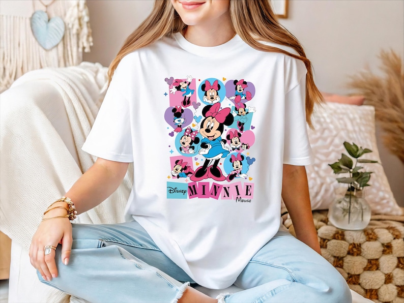 A woman wearing a white t-shirt with a Minnie Mouse graphic and text, sitting on a couch.