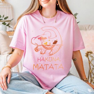 a woman sitting on a couch wearing a pink shirt