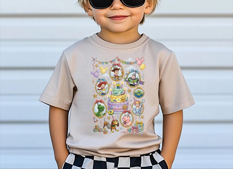 A young boy wearing a t-shirt with a colorful graphic of characters from the Toy Story movie, including Woody, Buzz Lightyear, and other beloved characters.