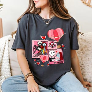 A woman wearing a black t-shirt with a graphic design featuring characters from the movie " Nightmare Before Christmas".
