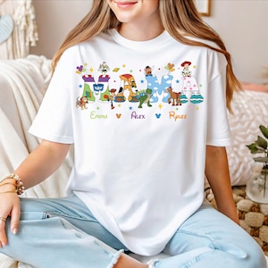 A woman wearing a white t-shirt with a colorful graphic design featuring characters from the Toy Story franchise.