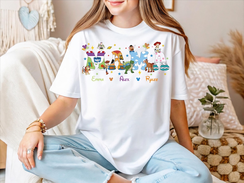 A woman wearing a white t-shirt with a colorful graphic design featuring characters from the Toy Story franchise.