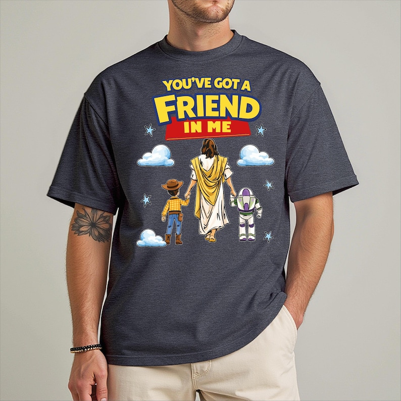 A man wearing a black t-shirt with a graphic design featuring a character from the Toy Story franchise, along with the text "You've got a friend in me" and a Bible verse.
