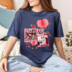 A woman wearing a blue t-shirt with a graphic design featuring characters from the movie " Nightmare Before Christmas".