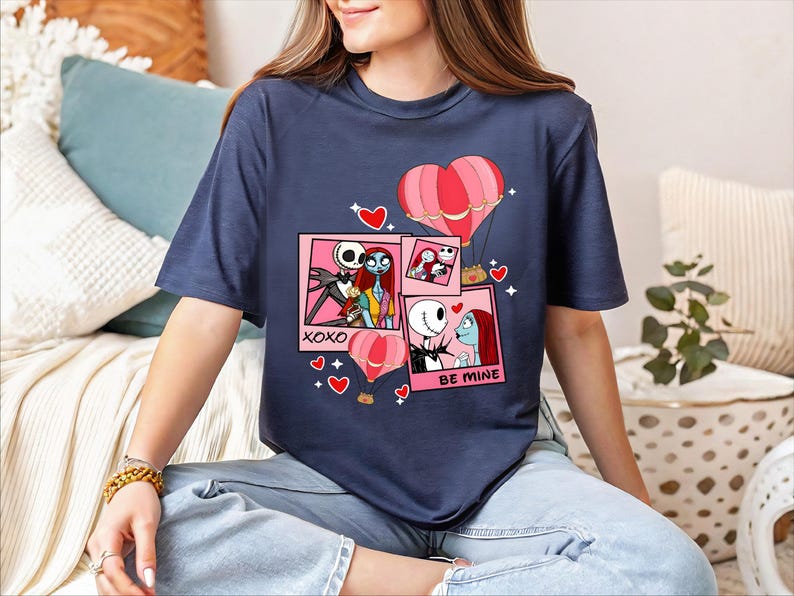 A woman wearing a blue t-shirt with a graphic design featuring characters from the movie " Nightmare Before Christmas".