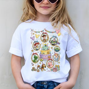 A young girl wearing a white t-shirt with a colorful graphic design featuring characters from the Toy Story movie.