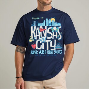 A man wearing a navy blue t-shirt with a graphic design featuring the text "KANSAS CITY" and various icons related to the city.