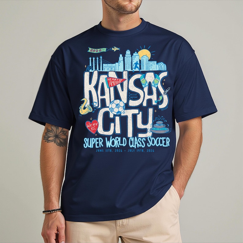 A man wearing a navy blue t-shirt with a graphic design featuring the text "KANSAS CITY" and various icons related to the city.