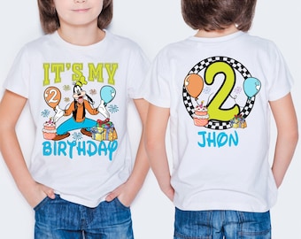 May include: White t-shirt with a colorful graphic featuring Goofy holding balloons and a cake, with the text "IT'S MY BIRTHDAY". The back of the shirt has a large number 2, balloons, and the name "JHON".
