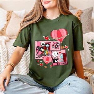 A woman wearing a green t-shirt with a graphic design featuring characters from the movie " Nightmare Before Christmas".