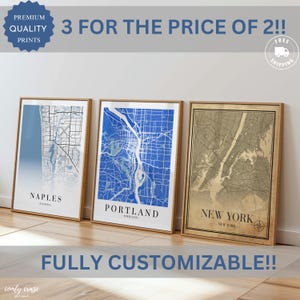 May include: Three framed city map prints. The maps are of Naples, Florida, Portland, Oregon, and New York, New York. The prints are in shades of blue and tan, with the city names below. The text "3 for the price of 2!!" is at the top.