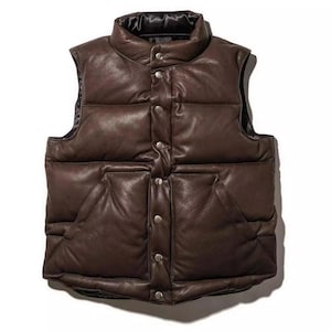 May include: A brown leather puffer vest with a high collar and a button-up front. The vest has two front pockets and a quilted design. The vest is a dark brown color and has a shiny finish.