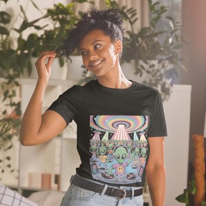 Könnte beinhalten: Schwarzes T-Shirt mit einem farbenfrohen Grafikdesign von Aliens auf einer Party. Das Design zeigt einen DJ, eine regenbogenfarbene UFO und tanzende Aliens. Das T-Shirt ist aus weichem Material.