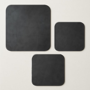 May include: A set of three black square trays with rounded corners. The trays are arranged in a group, with one large tray at the top, a medium tray to the right, and a smaller tray at the bottom. The trays have a matte finish.