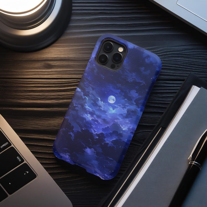 Puede incluir: Funda de tel&eacute;fono azul oscuro con un dise&ntilde;o de cielo nocturno, que incluye nubes y una luna llena. La funda est&aacute; hecha de un material duradero y est&aacute; dise&ntilde;ada para proteger el tel&eacute;fono de ara&ntilde;azos e impactos. La funda se muestra sobre una superficie de madera.