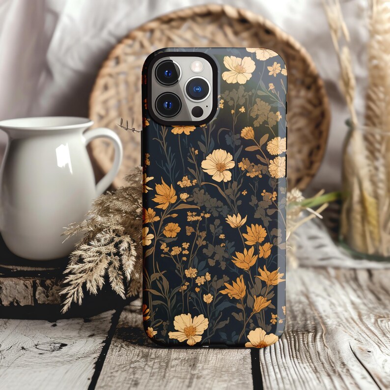 May include: A black phone case with a floral pattern. The flowers are yellow and orange on a dark background. The case has a camera lens cutout.