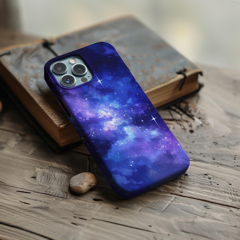 May include: A phone case with a galaxy design. The case is blue and purple with white stars. The case has a camera cutout.