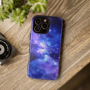 May include: A purple and blue galaxy phone case with a watercolor effect and white stars. The case has a raised camera bump with three lenses.