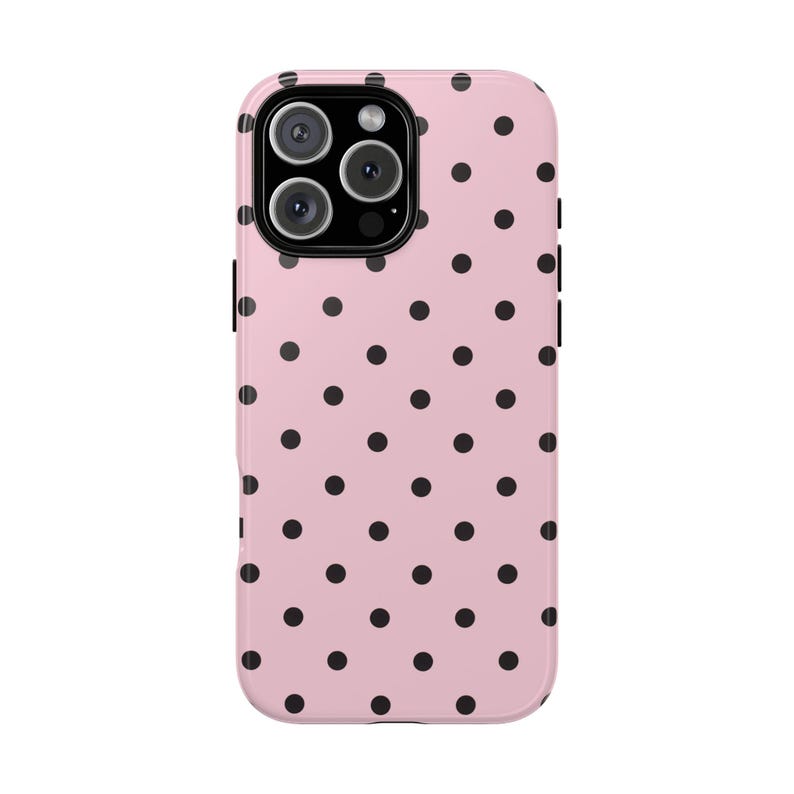 May include: A pink phone case with a black polka dot pattern. The case has a glossy finish and a camera cutout at the top. The case is designed to fit a smartphone.
