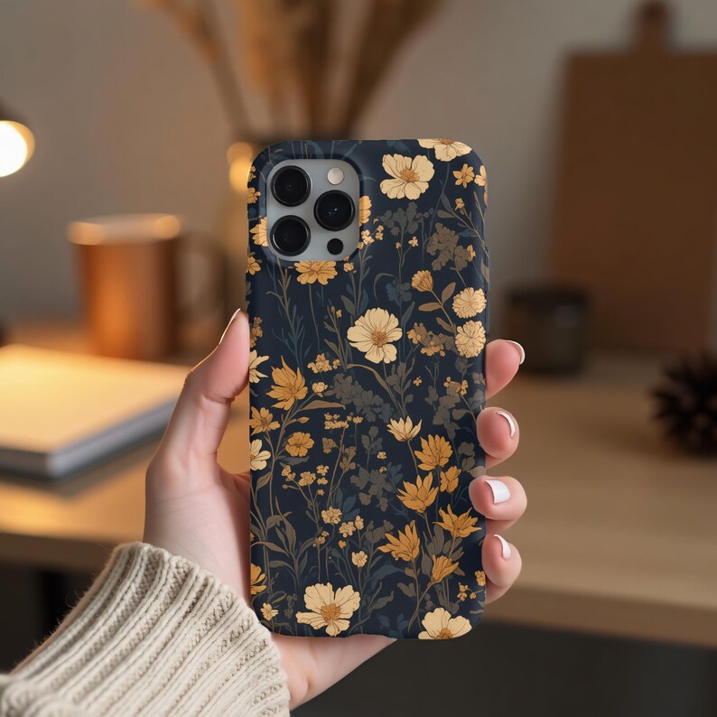 May include: A black phone case with a floral pattern featuring yellow and white flowers on a dark blue background.